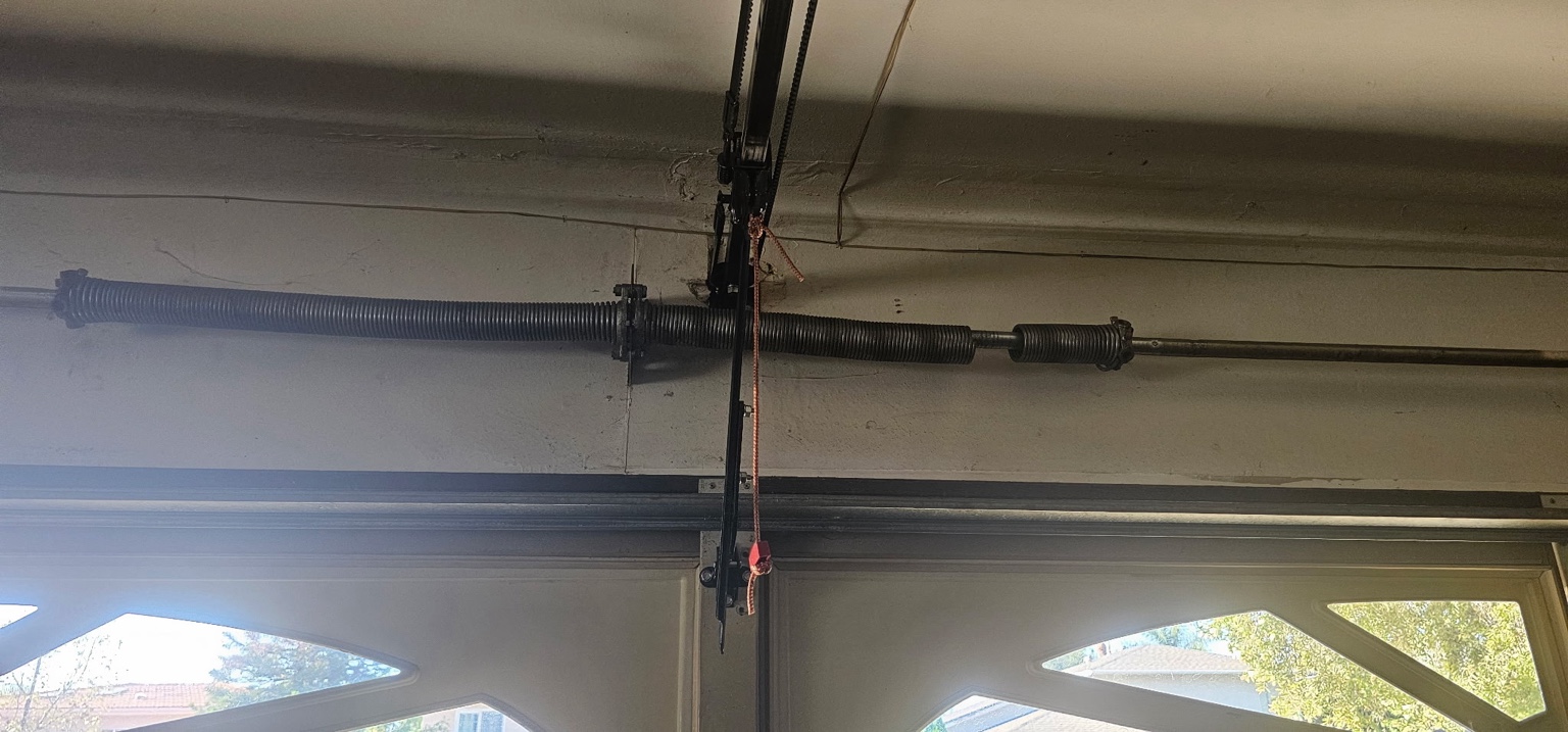 A visible break in the right torsion spring above the garage door before replacement